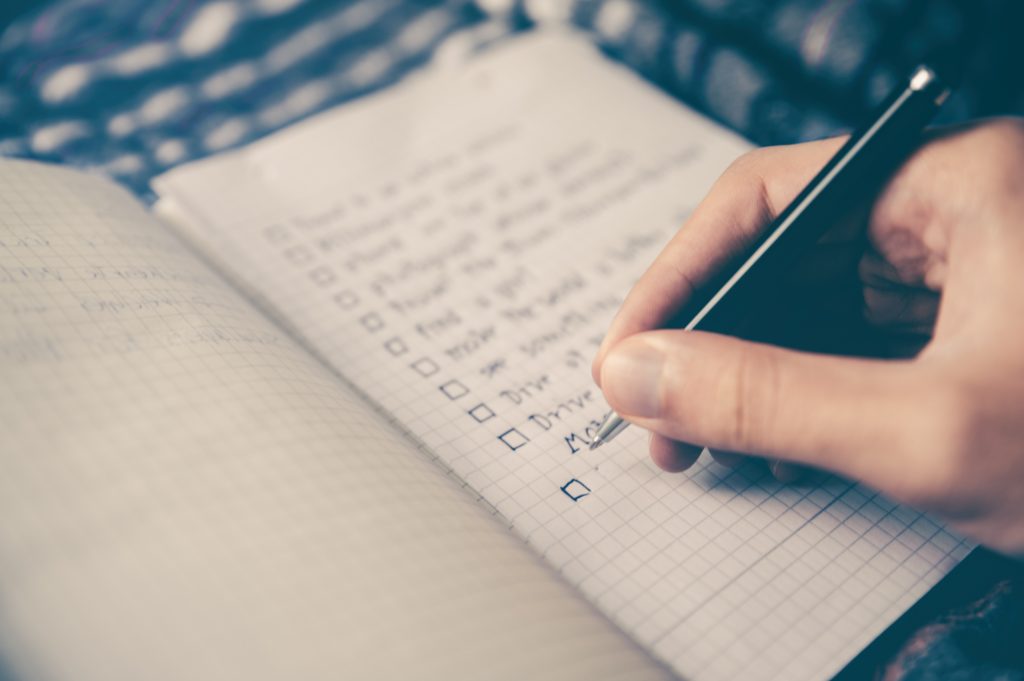 adult writing a checklist in a journal