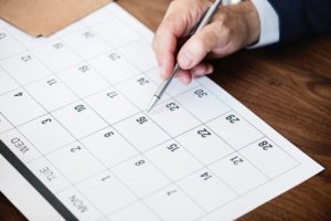 man holding pen over a monthly calendar image
