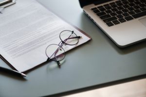 glasses sitting beside computer on top of paperwork