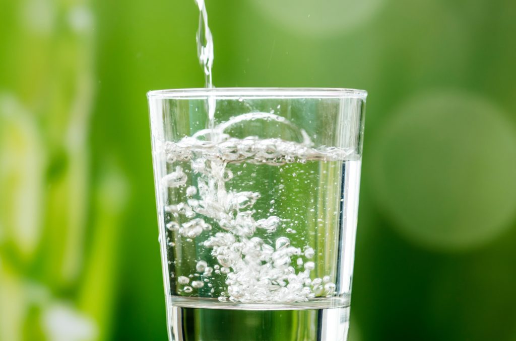 water in a clear glass with green background