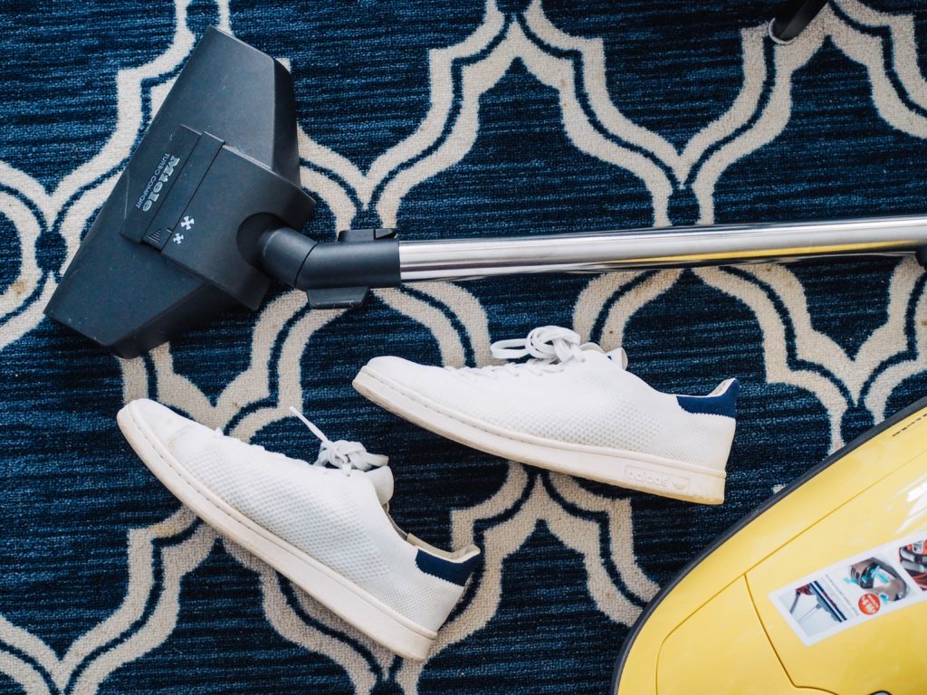 sneakers beside vacuum on carpet