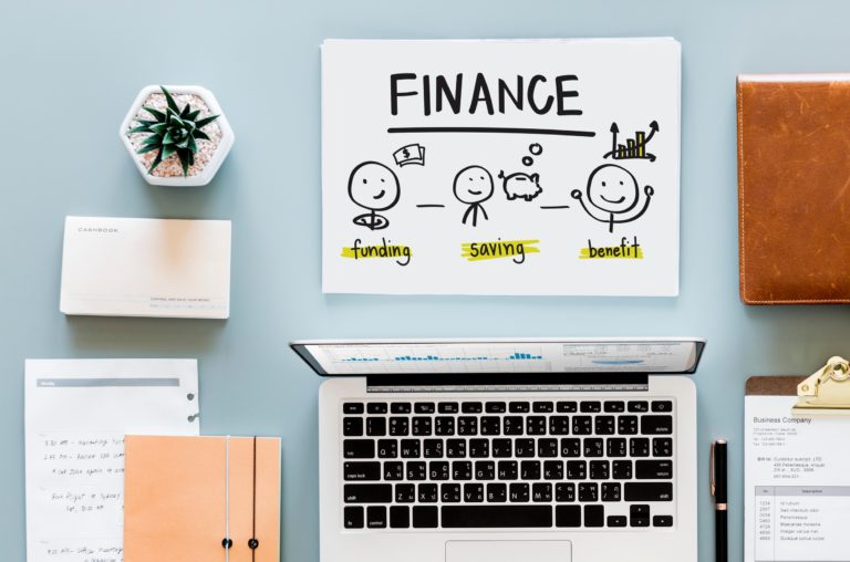 the word finance written on paper beside a laptop computer