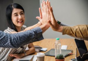 people giving high five around table indicating success